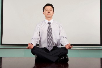 Photo of a man meditating in a conference room